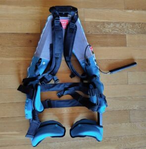 空気圧式のアシストスーツが床に置かれている。ポンプで空気を注入することで内部のエアバッグが膨らみ、腰や太ももへの負担を軽減する仕組みになっている。